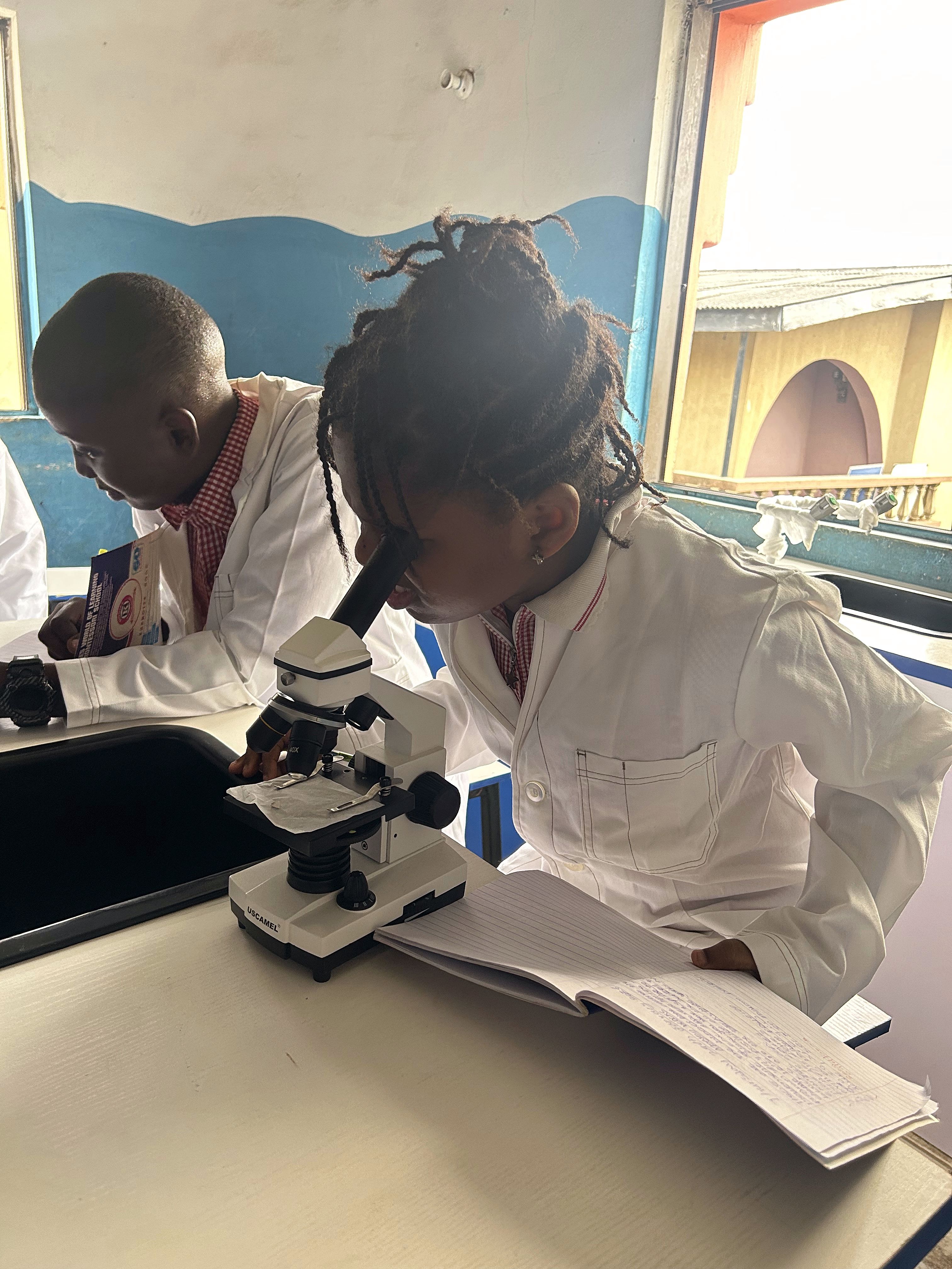 Students in lab coats working with a microscope